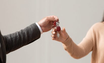 Real Estate Agent Giving Keys To Buyer Handover Concept. Close up cropped view of professional real estate agent wearing suit holding in hand and giving keys to young female buyer. Woman taking key of future new apartment